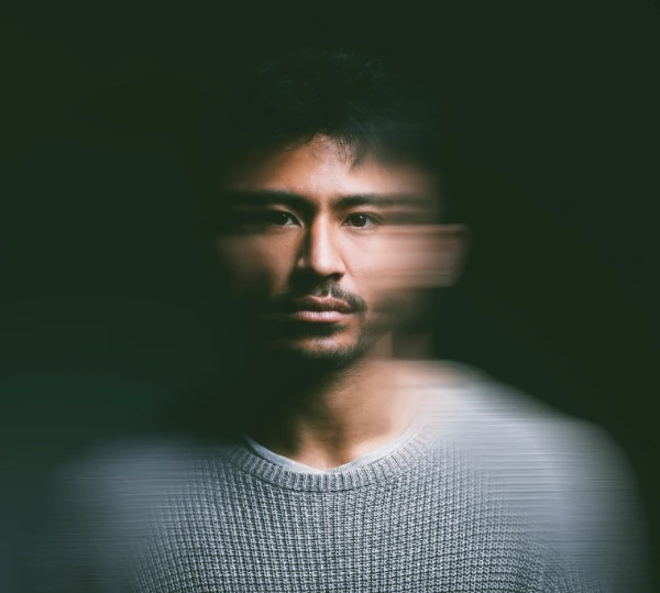 A portrait of a man with a blurred effect around his face, giving a sense of motion or confusion.