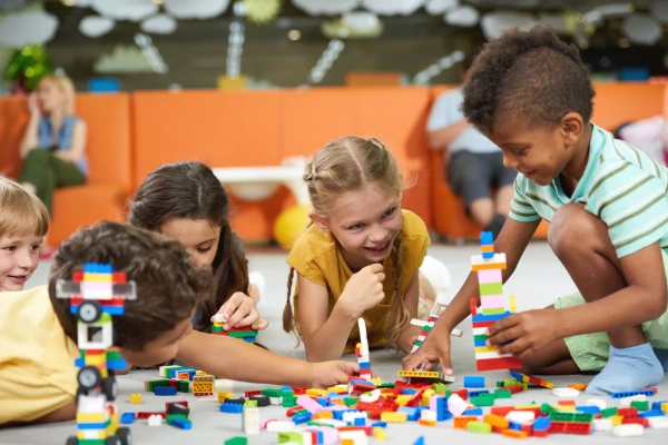 A group of children playing with colorful building blocks at a table, deeply focused and enjoying the activity.