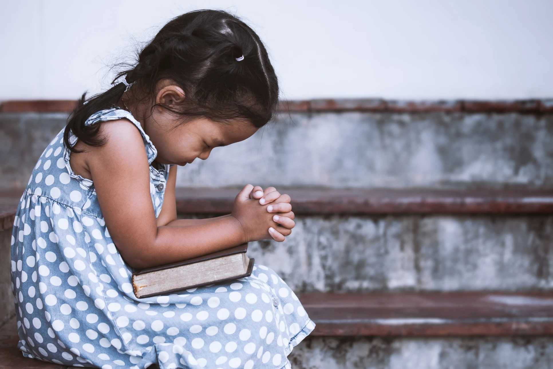 Young Girl Praying with a Bible