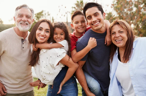 A cheerful, diverse family posing together outdoors, including parents and two children.