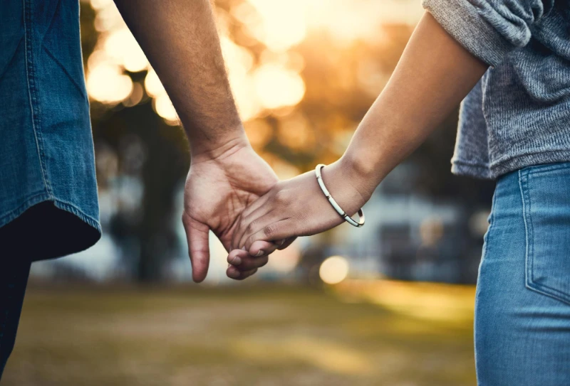 a couple holding hands walking into sunlight