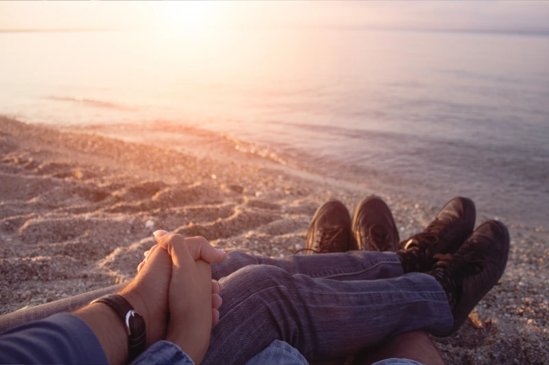 Couple holding hands and snuggling on the beach