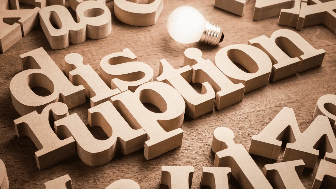 Wooden letters spell disruption on a wooden surface, with a lit lightbulb placed above the word, symbolizing innovation or new ideas.